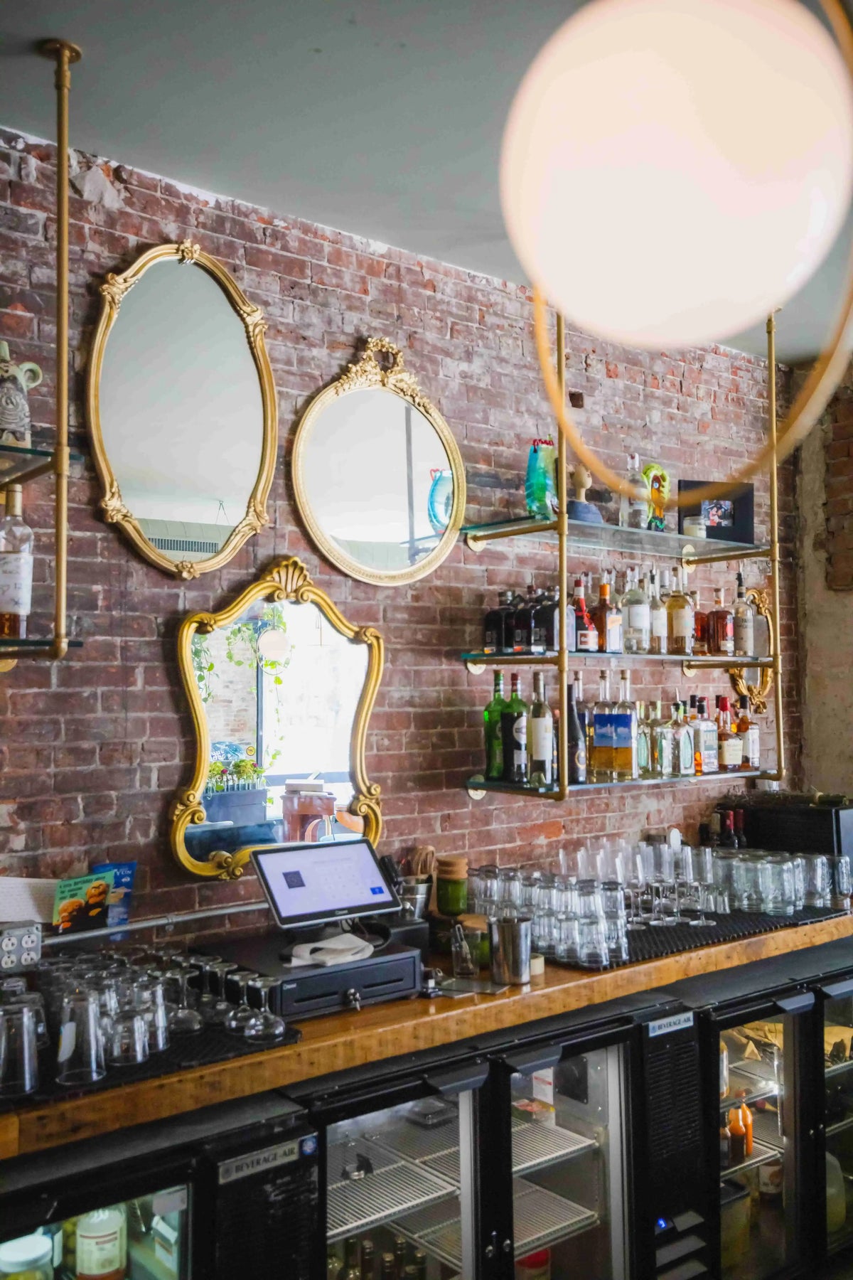 Back bar wall with shelves of bottles and glasswear and mirrors