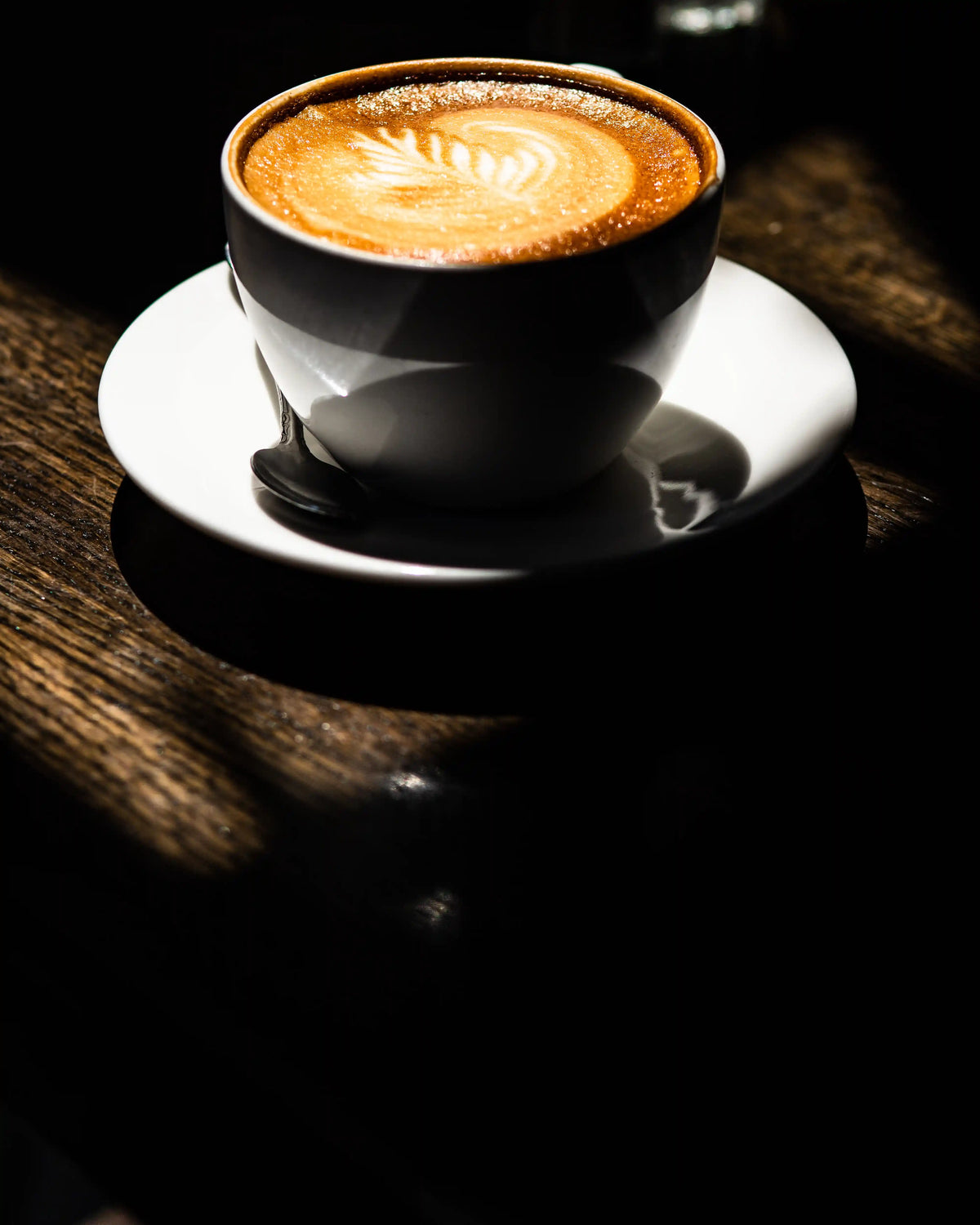 Bean2Bean cappuccino on a white saucer on a wooden table
