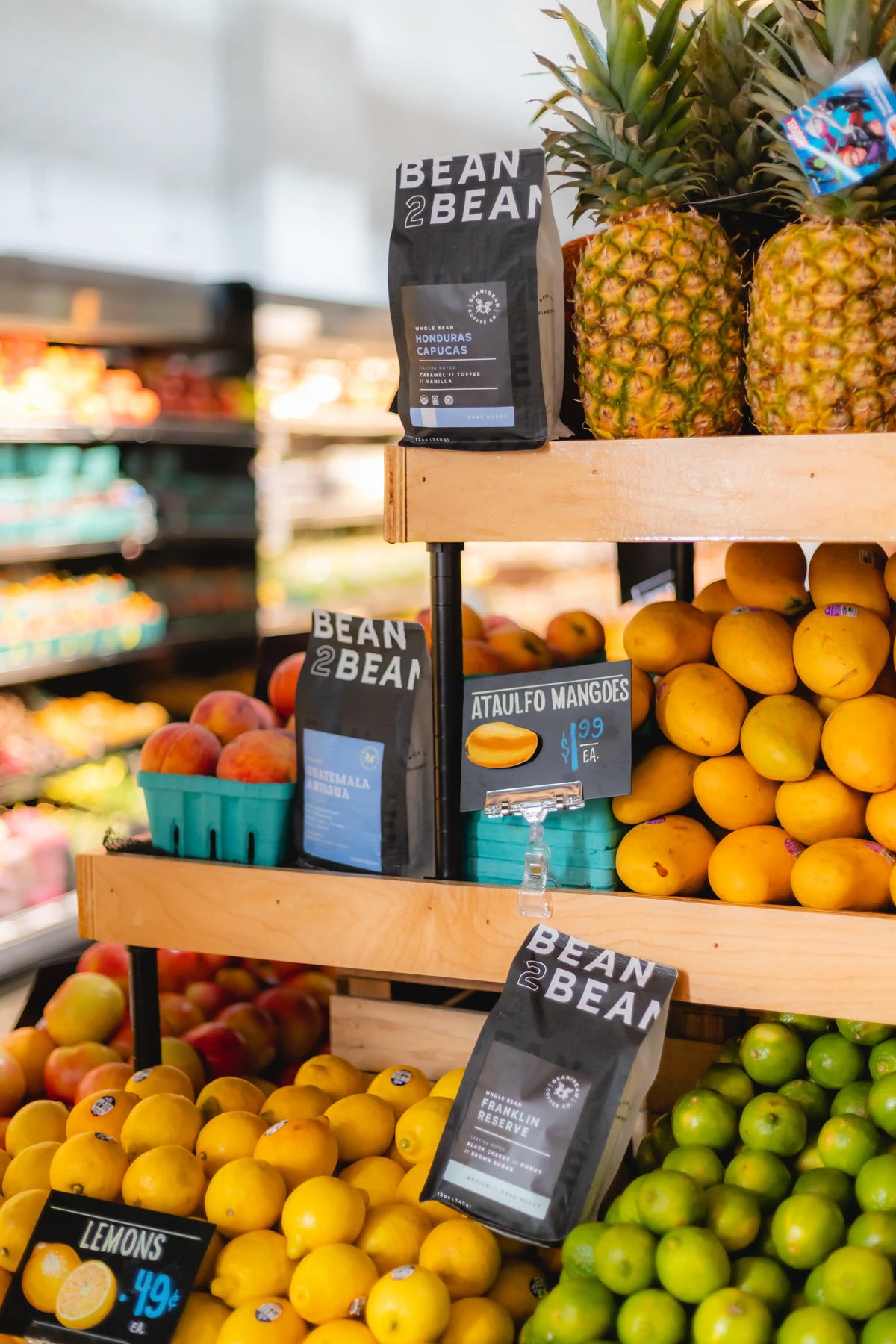 Fruit and vegetable display with 'Bean2Bean' coffee bags in Riverwards produce grocery store.
