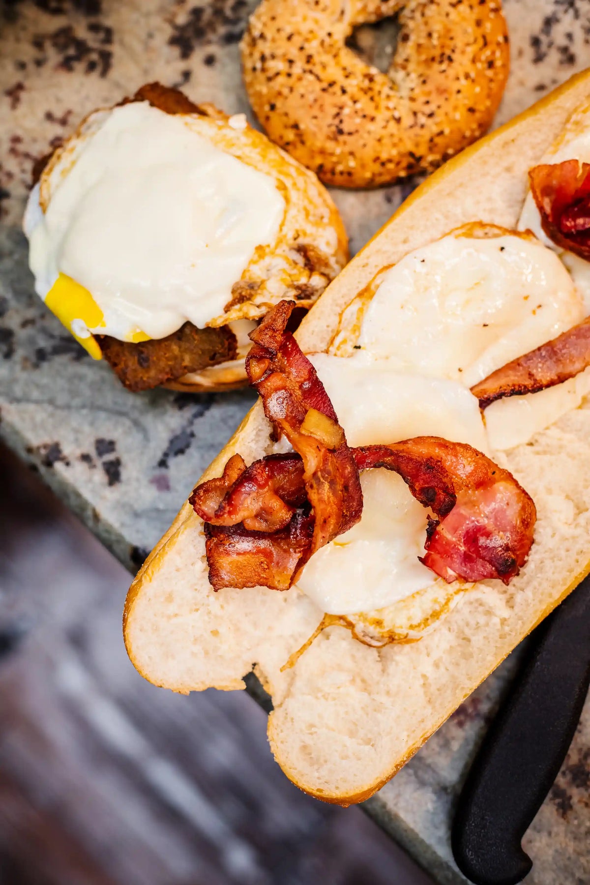 Overhead of two breakfast sandwiches being assembled, open-face