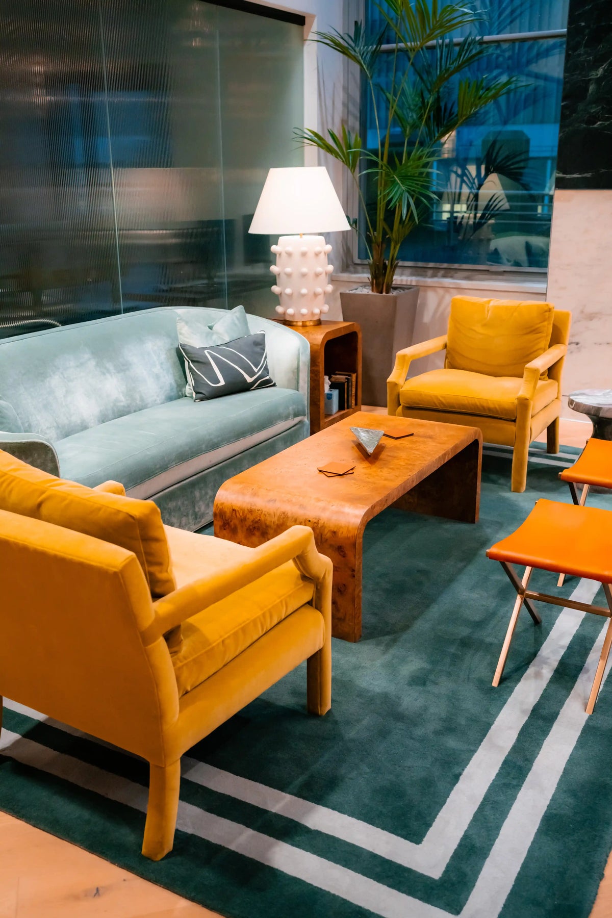 Modern offiec living area with yellow chairs, a green sofa, and a wooden coffee table.