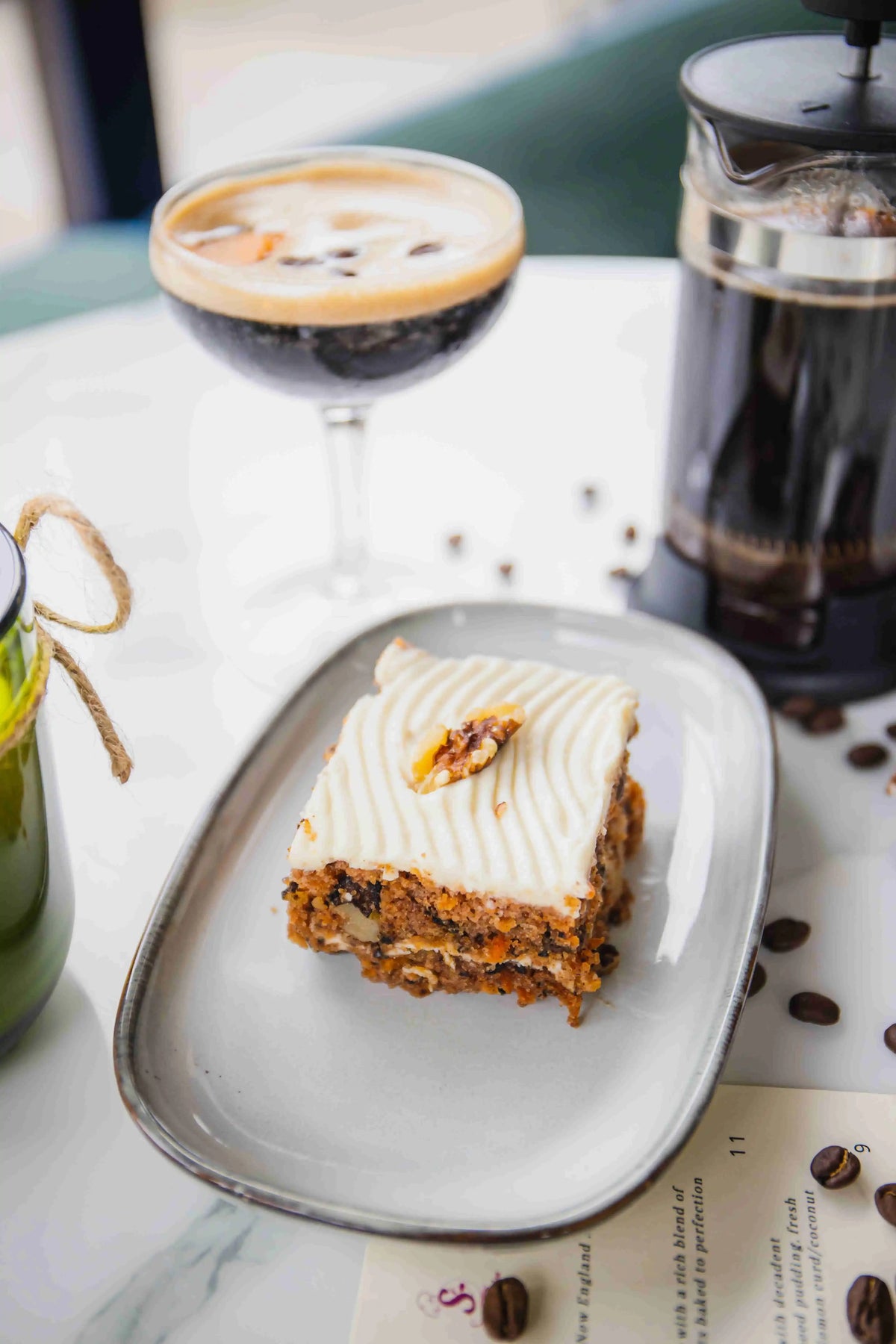 Carrot cake on elegant rounded white plate with Bean2Bean espresso martini blurred in background