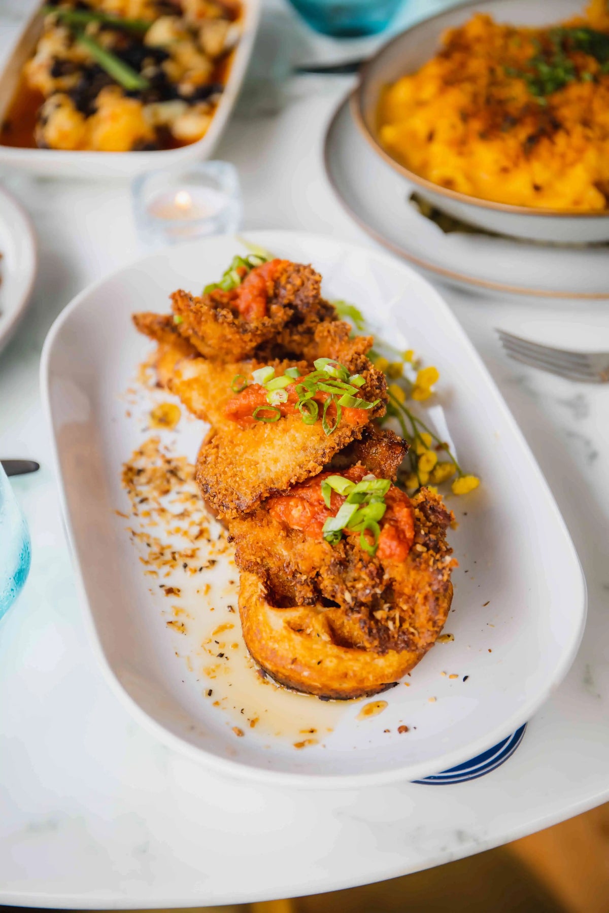 Fried chicken mushrooms over waffles on long white plate
