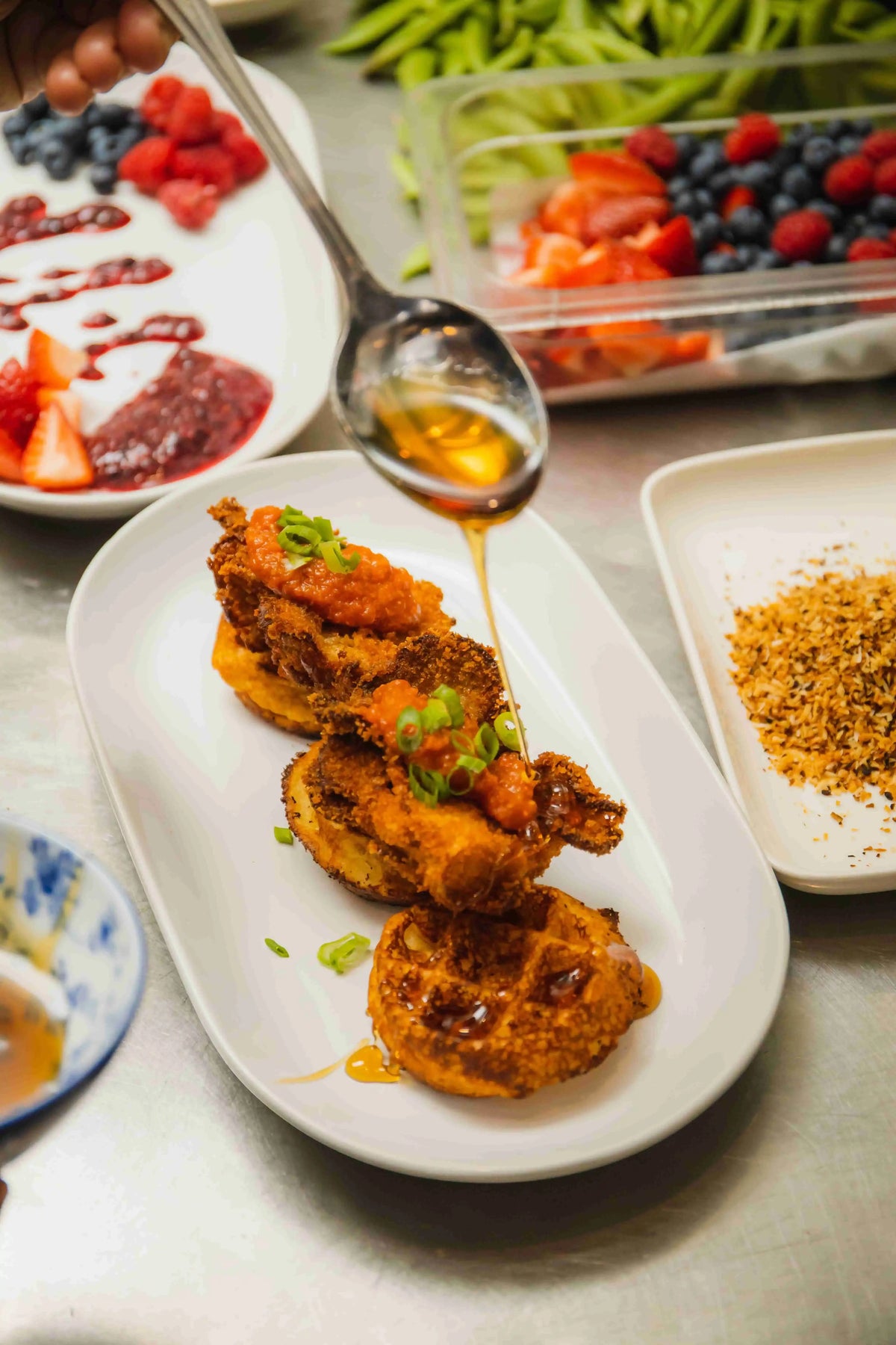 honey being drizzled over fried mushrooms and waffles