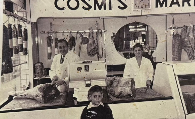 Vintage black and white photo of a butcher shop with a man, woman, and child.