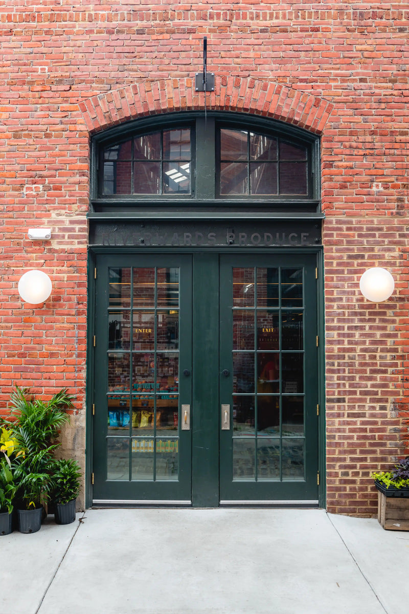 Green double doors with glass panels on Riverwards brick building entrance