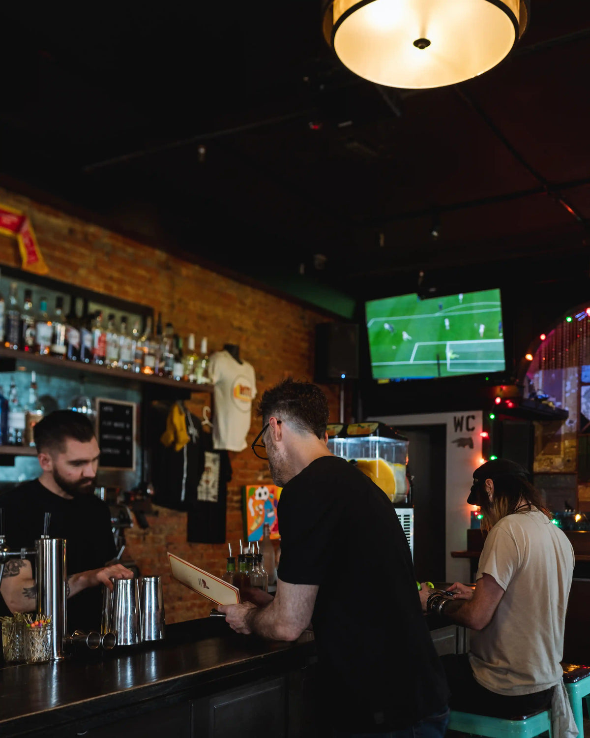 Bar scene with patrons and a sports game on a screen