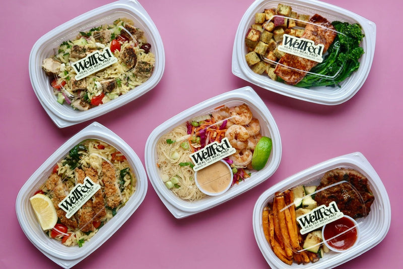 Five Be Wellfed meal containers on a pink background
