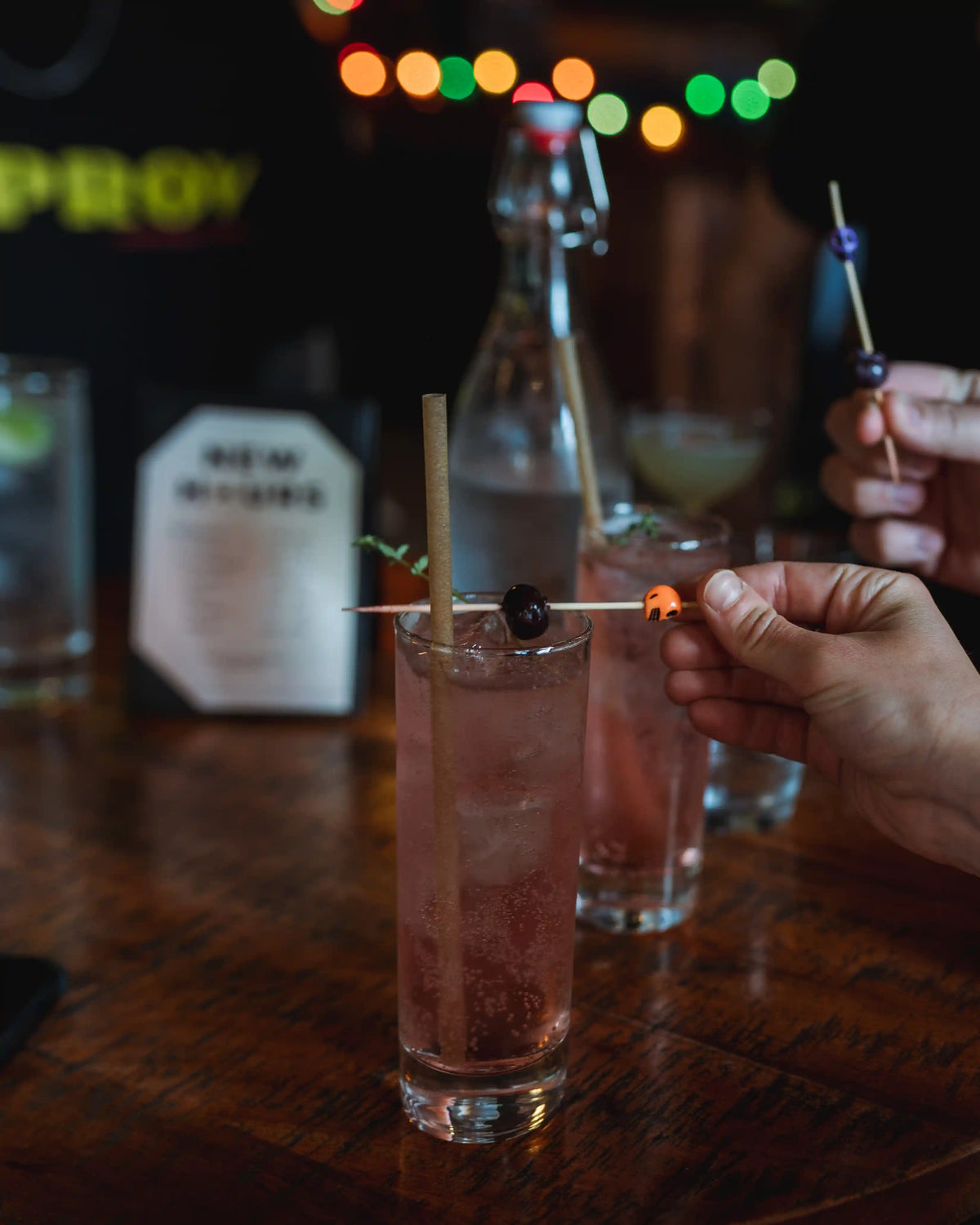 Pink cocktail with a skewer in a glass on a bar counter with blurred background