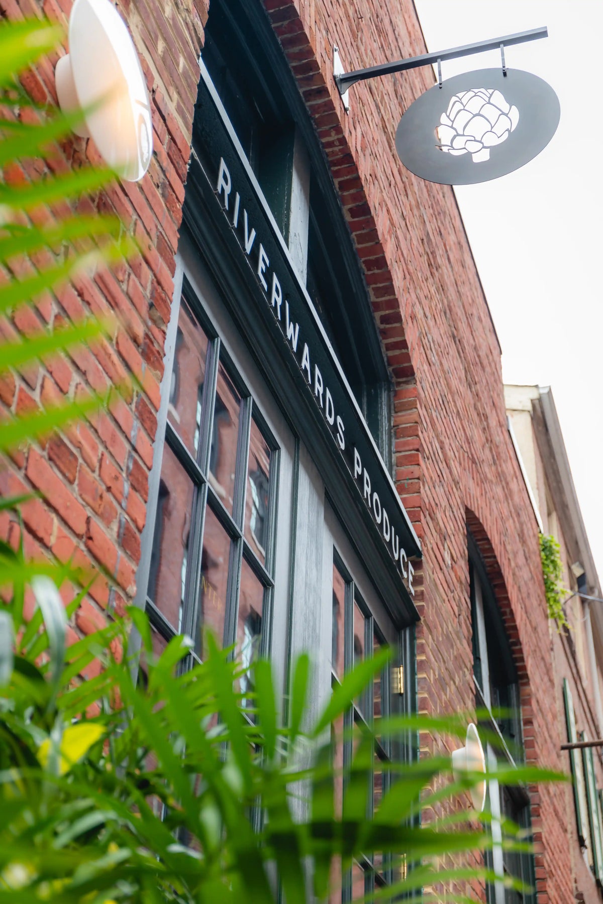 Brick building with 'Riverwards Produce' sign and greenery