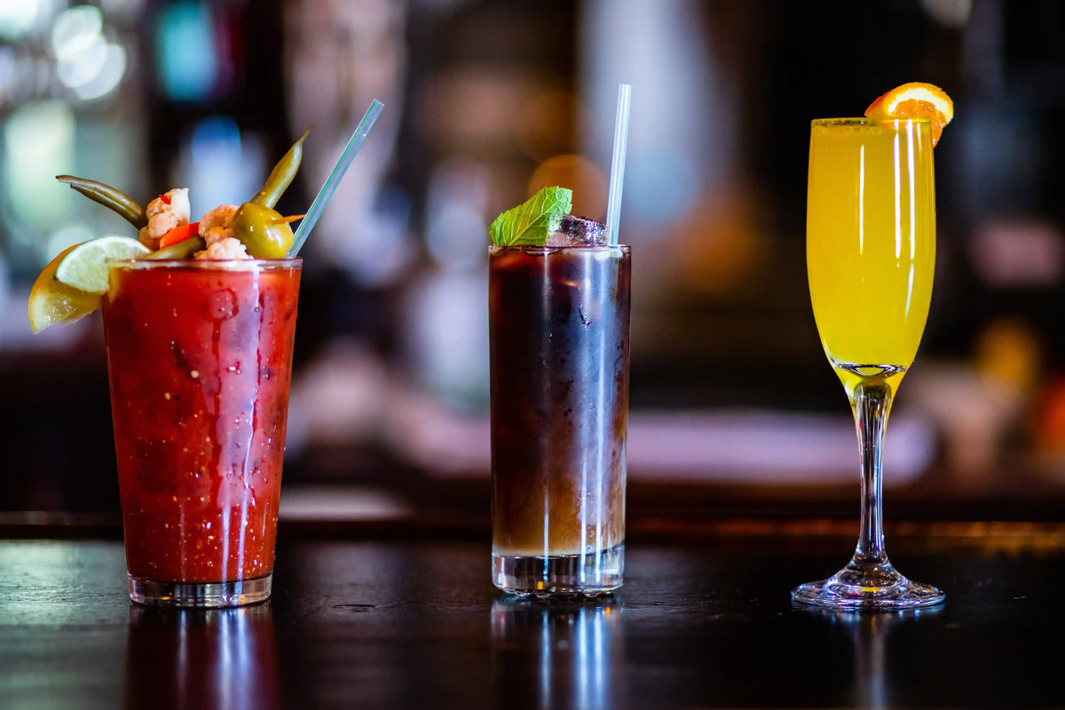 Three cocktails on a bar counter with a blurred bar background
