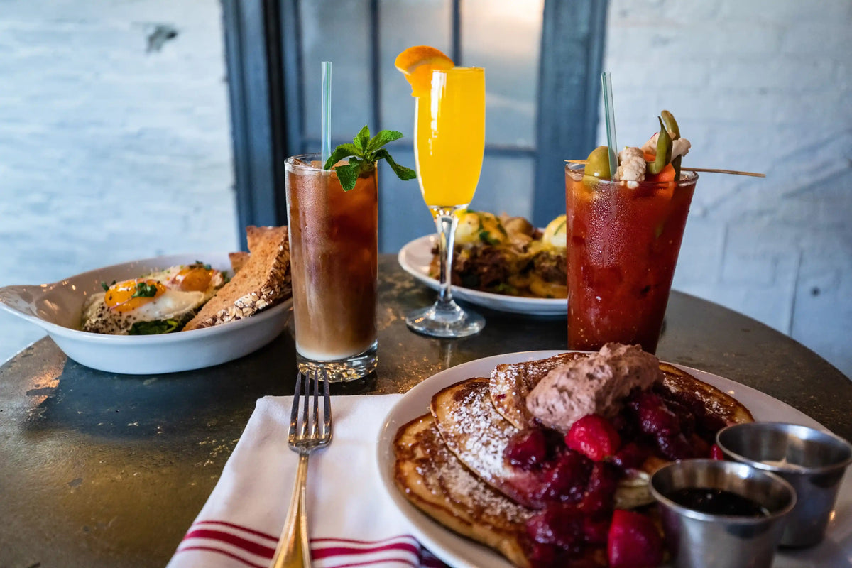 Breakfast setting with pancakes, fruit, and drinks on a table.