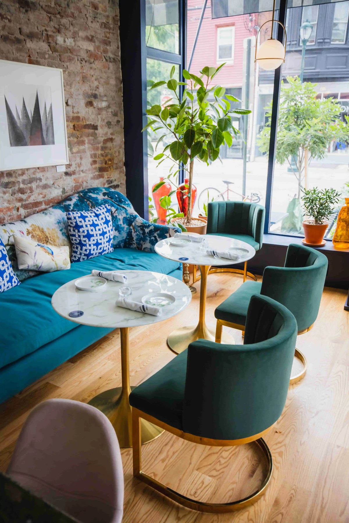 two indoor white round tables with gold bottoms facing a blue velvet counch inside of Fitz on 4th Philadelphia