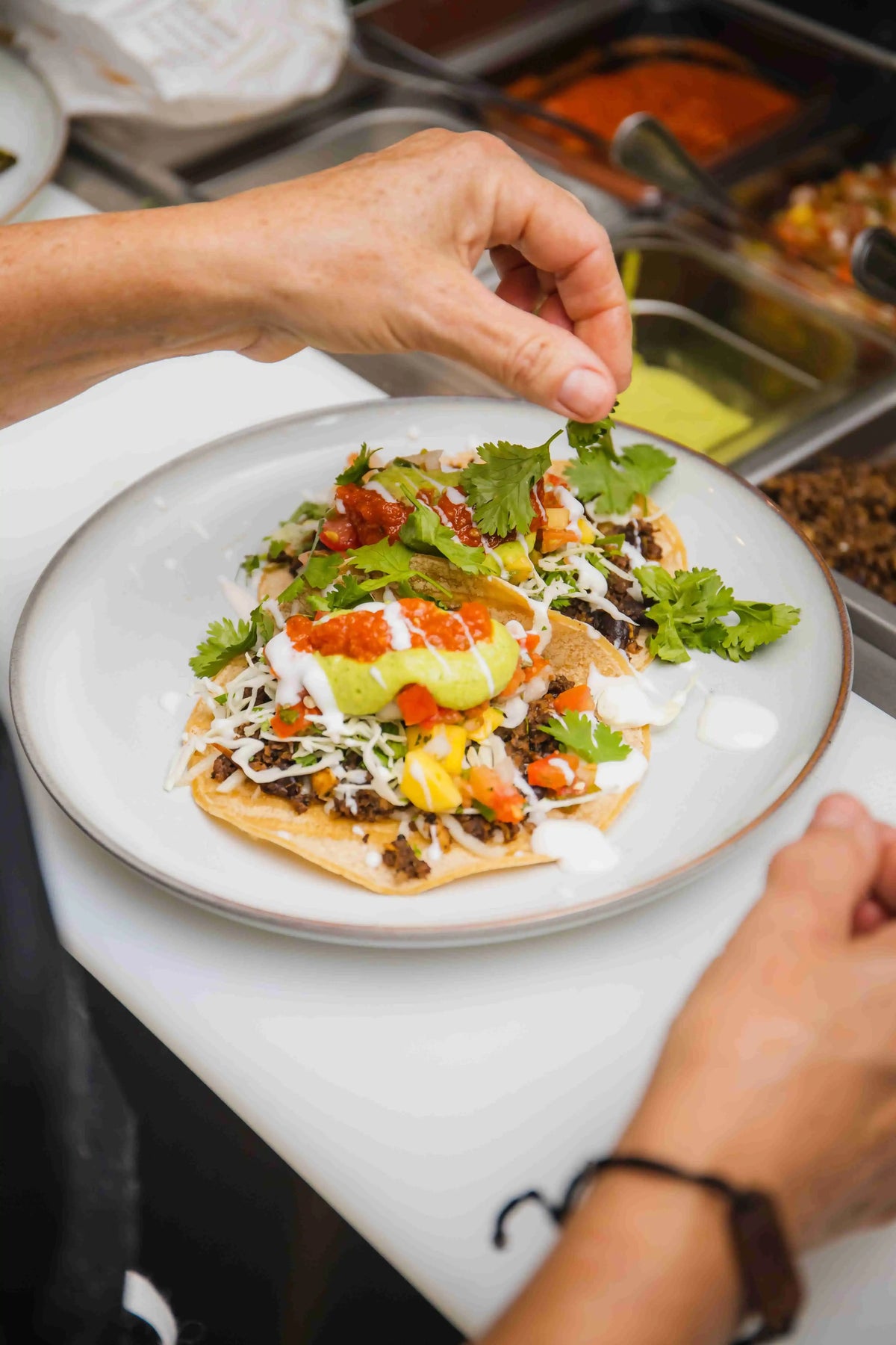 Soft-shell traditional tacos being prepared in a kitchen on a prep counter