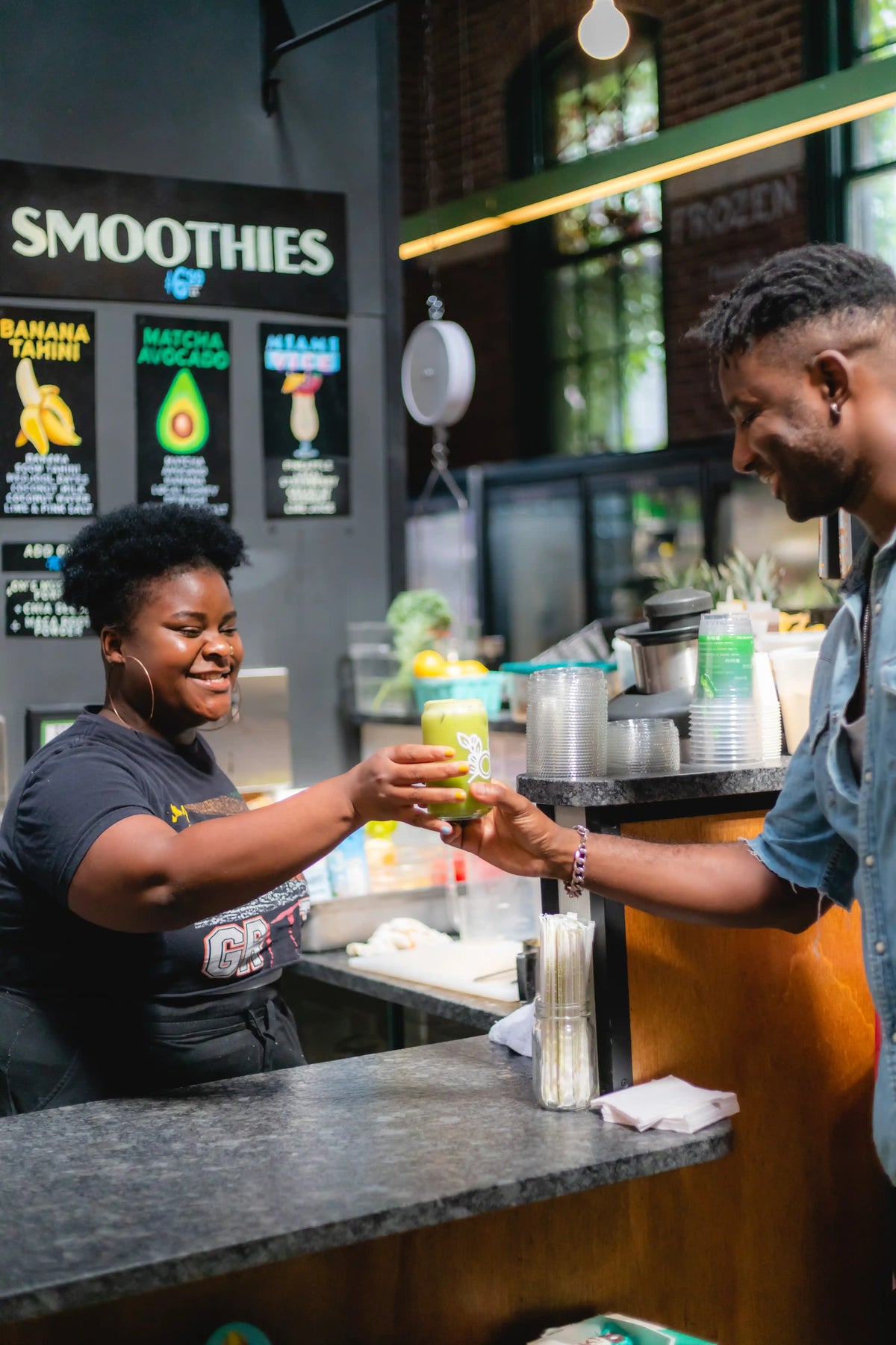 Person receiving a smoothie from a barista in Riverward's Produce smoothie shop.