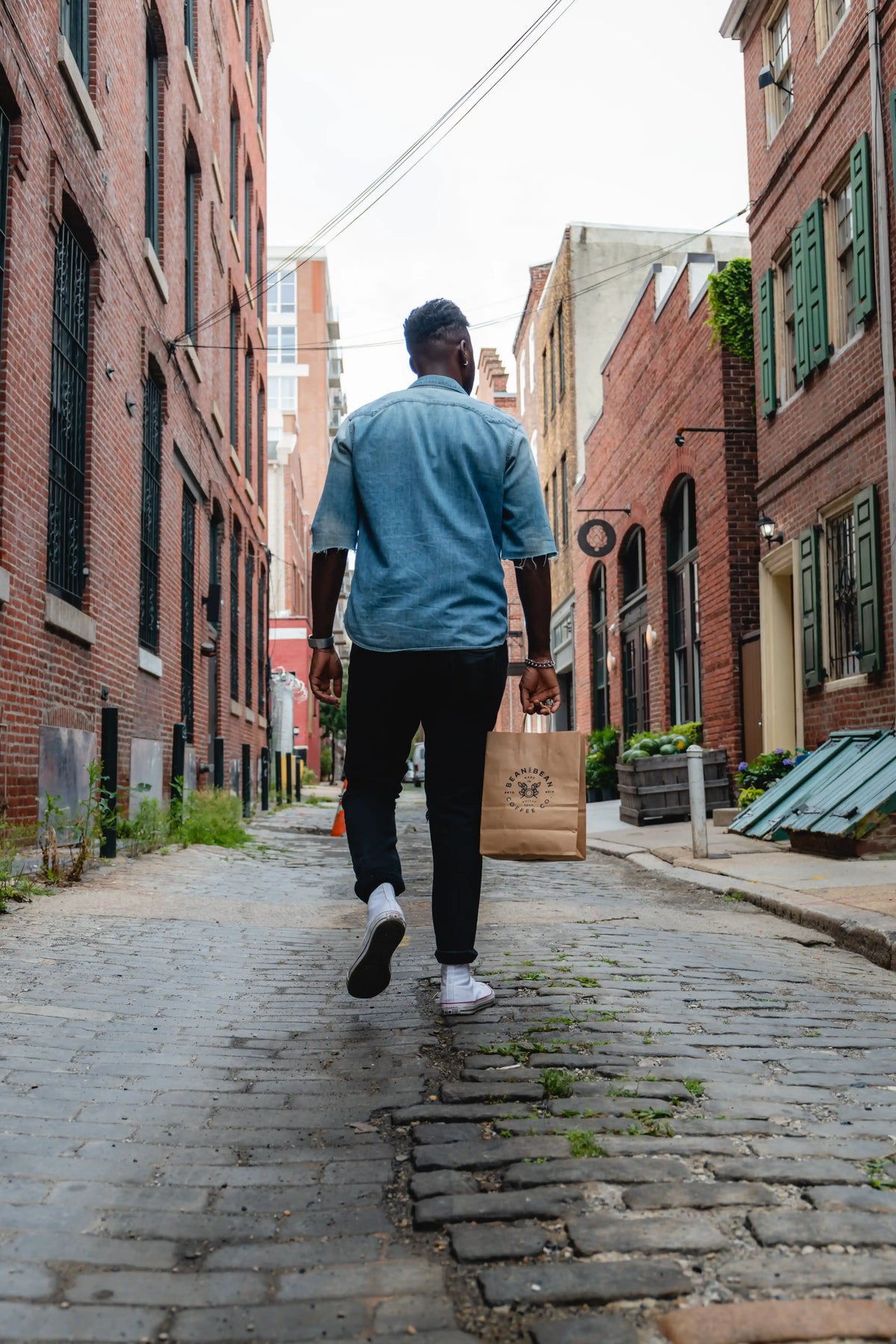 Man walking down a narrow alleyway between brick buildings