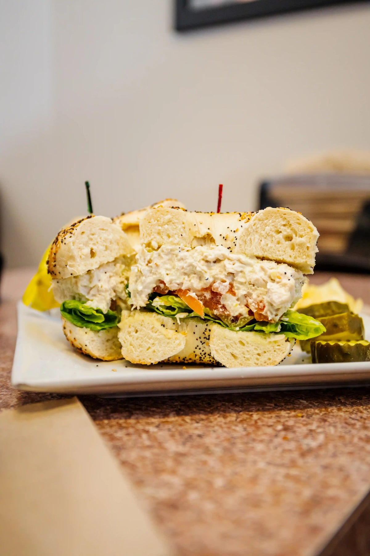 Half-eaten sandwich on a plate with pickles and a blurred background