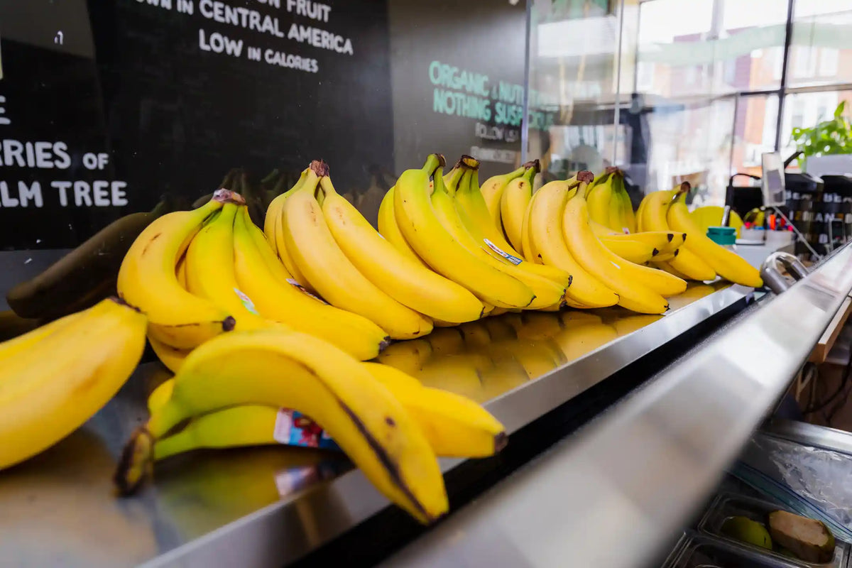 Bunches of bananas on a stainless steel counter inside Main Squeeze