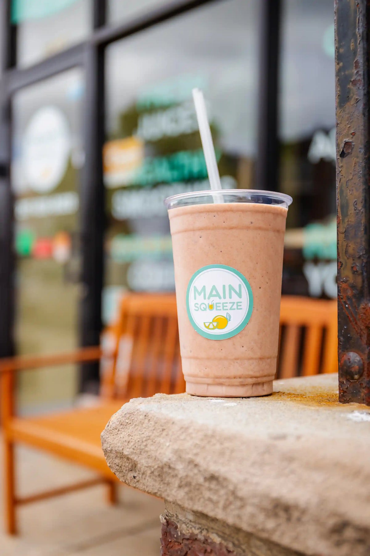 Pink smoothie with a straw on a ledge in front of a the Main Squeeze shop window