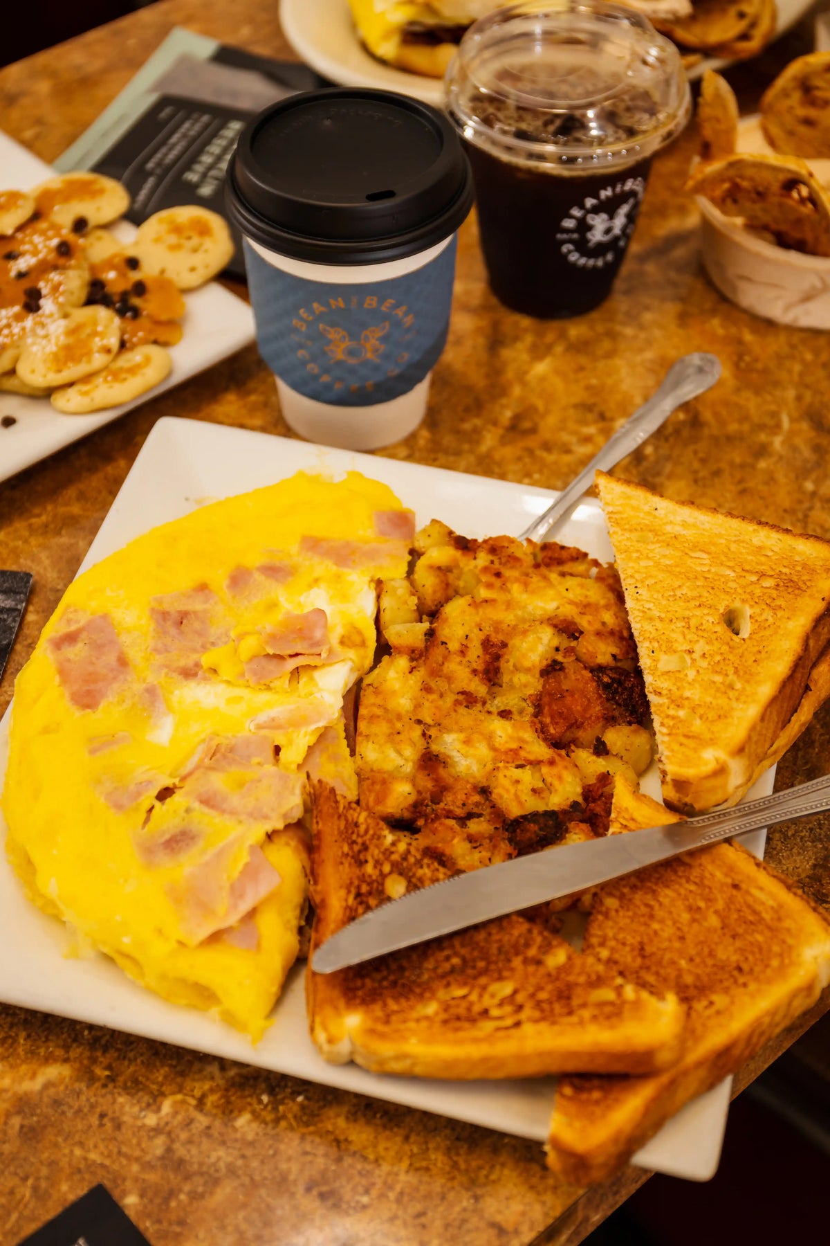 Breakfast setting with omelette, toast, and coffee on a wooden table.