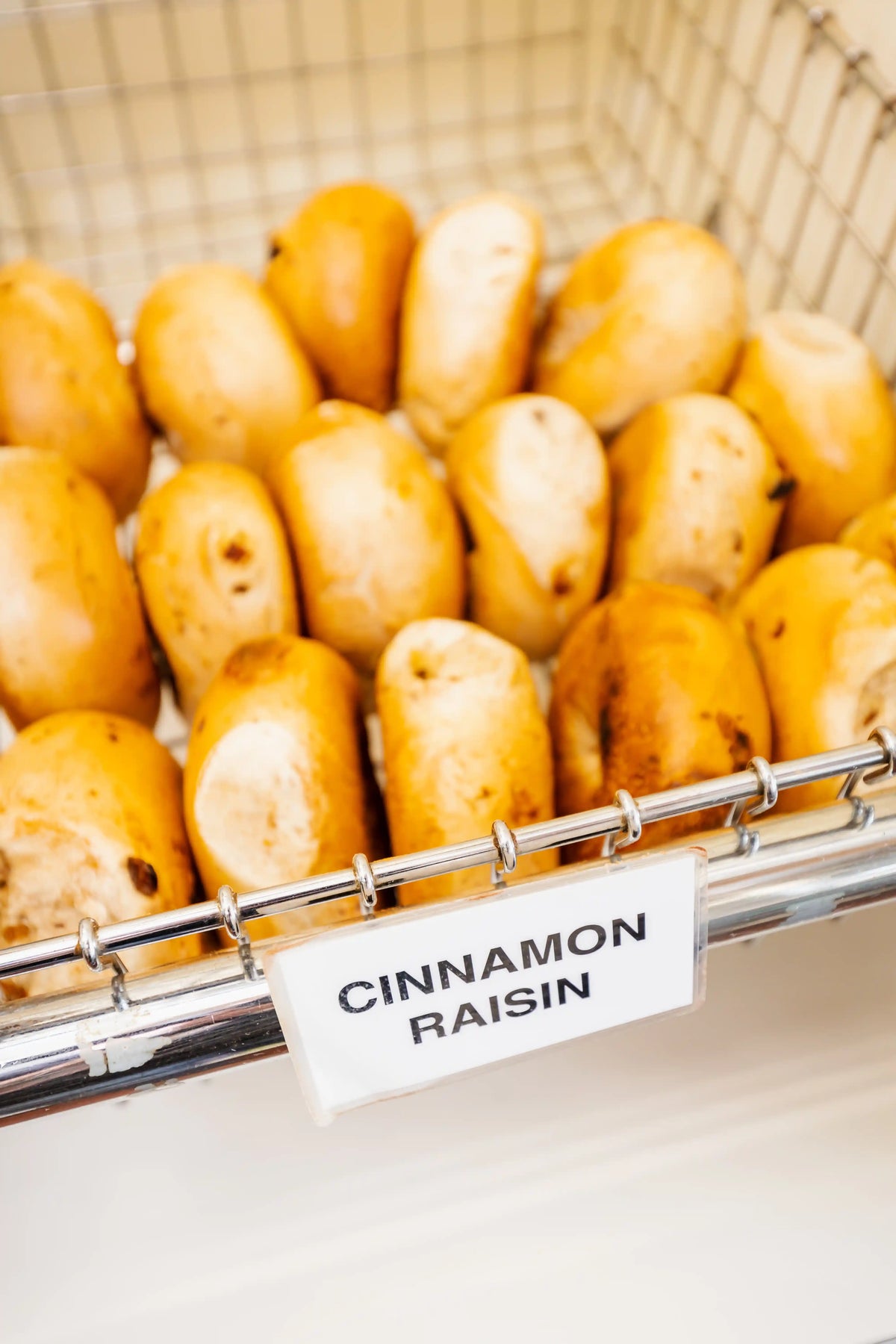 Basket of cinnamon raisin bread rolls with a label on a white background
