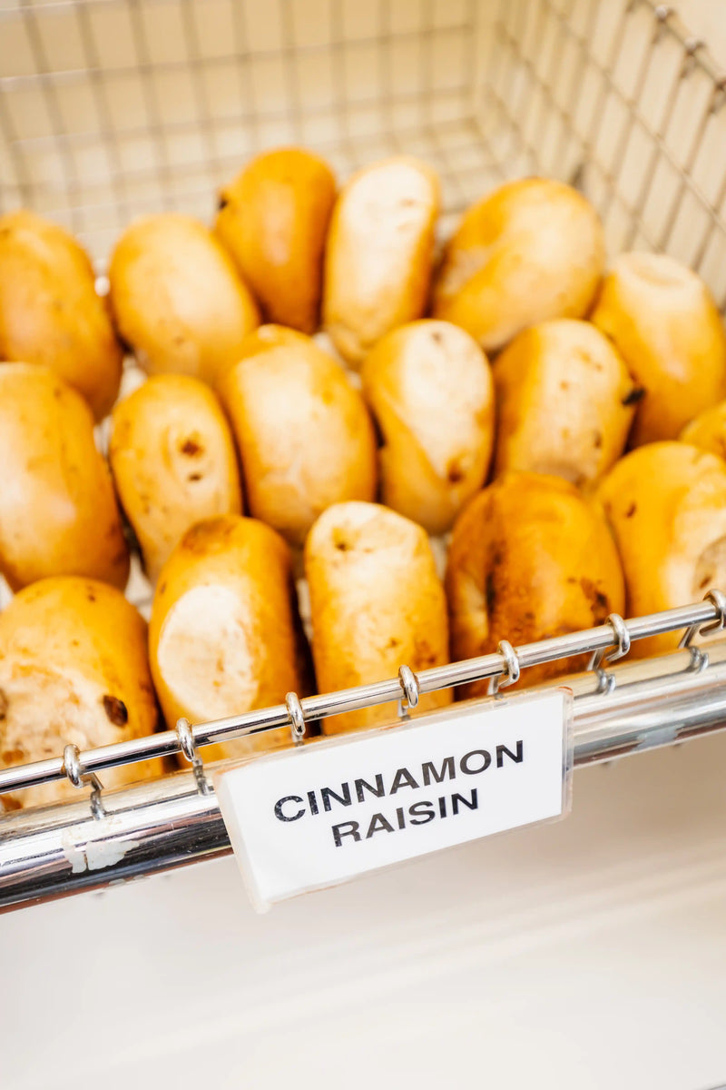 Basket of cinnamon raisin bread rolls with a label on a white background