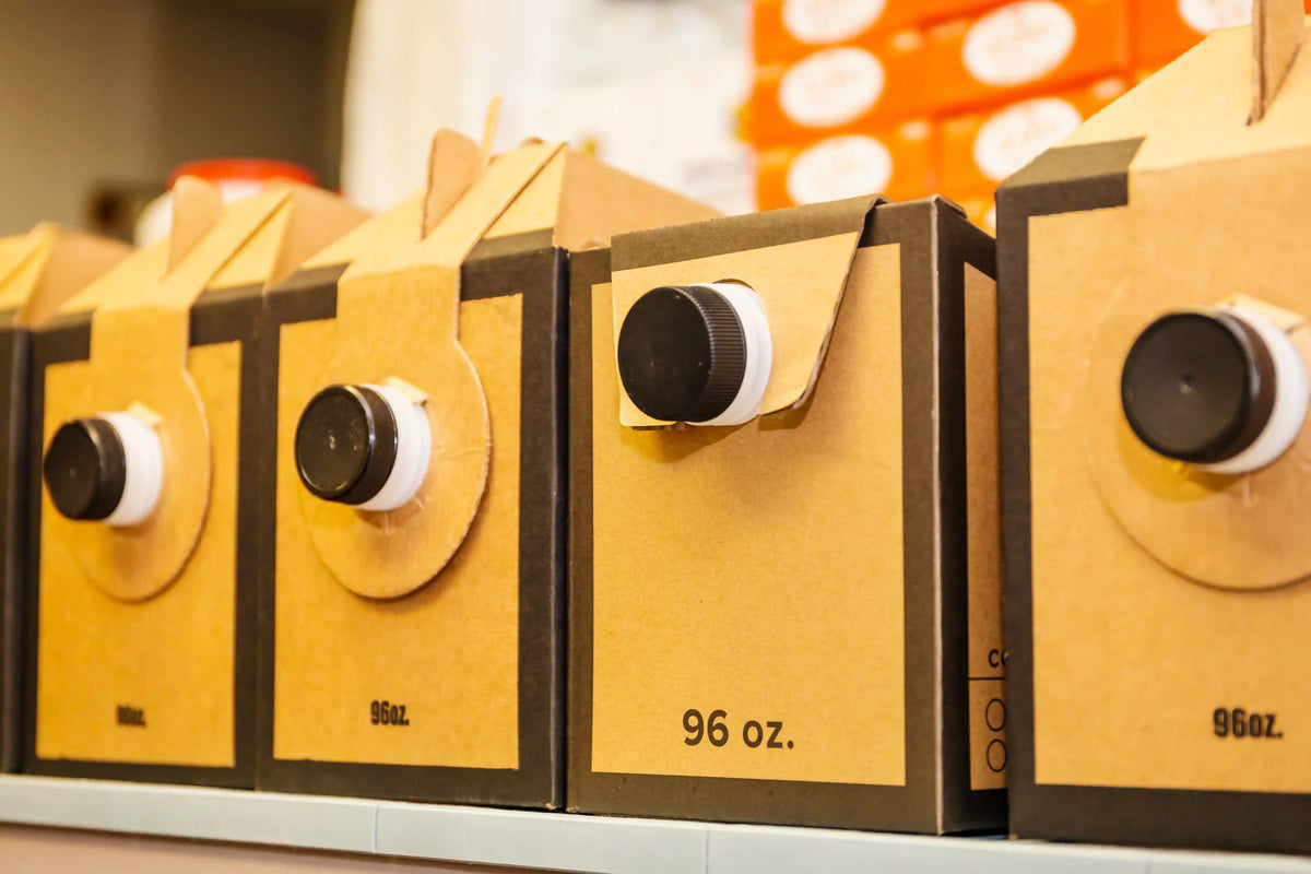 Row of cardboard boxes with black and white labels on a shelf.