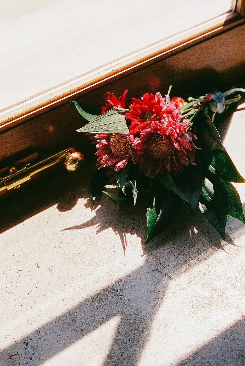 Floral arrangement on a wooden surface with sunlight casting shadows