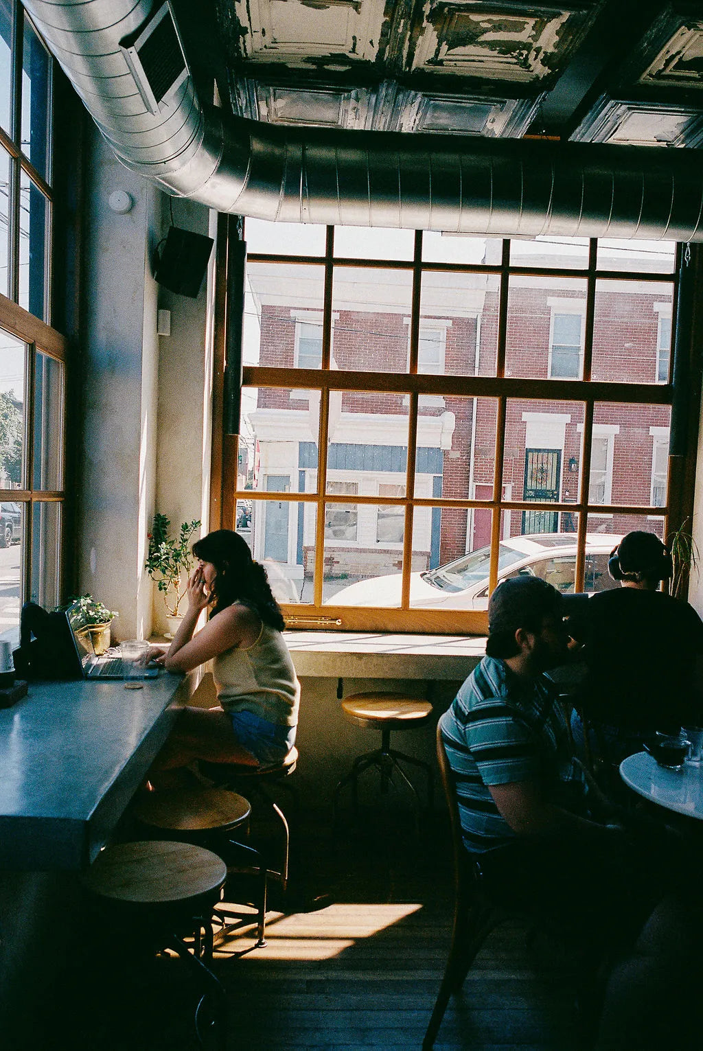 People sitting at a cafe with large windows showing a street view.