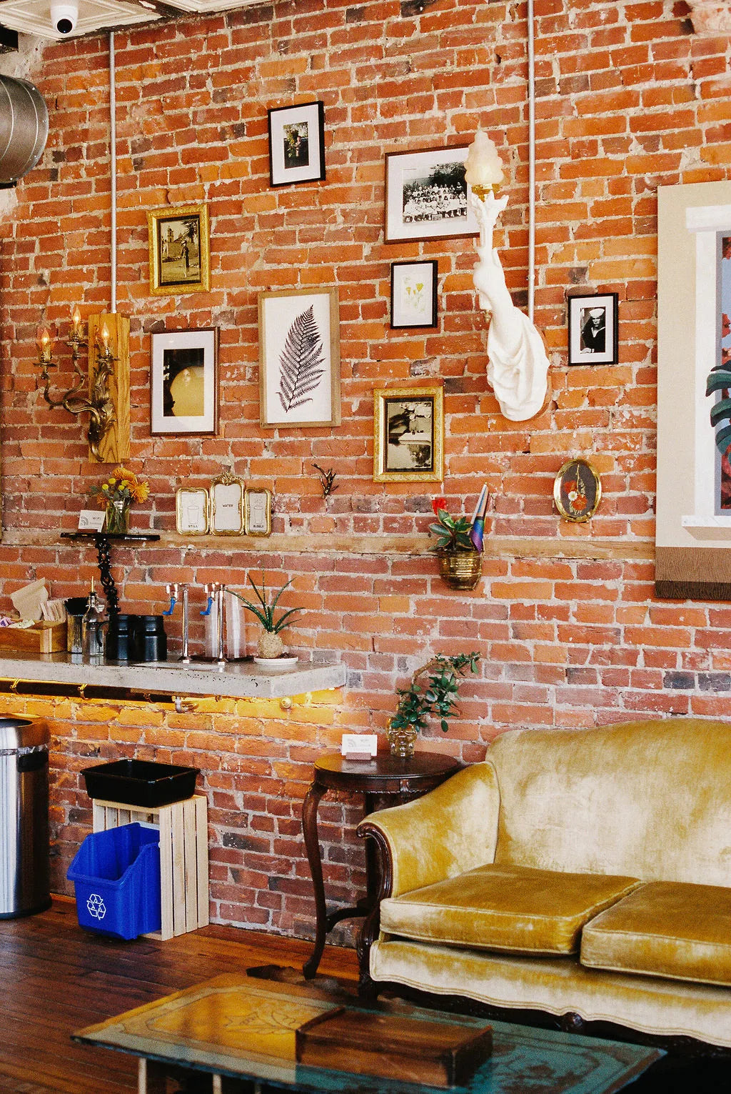 Cafe front room with brick wall, yellow sofa, and decorative items.