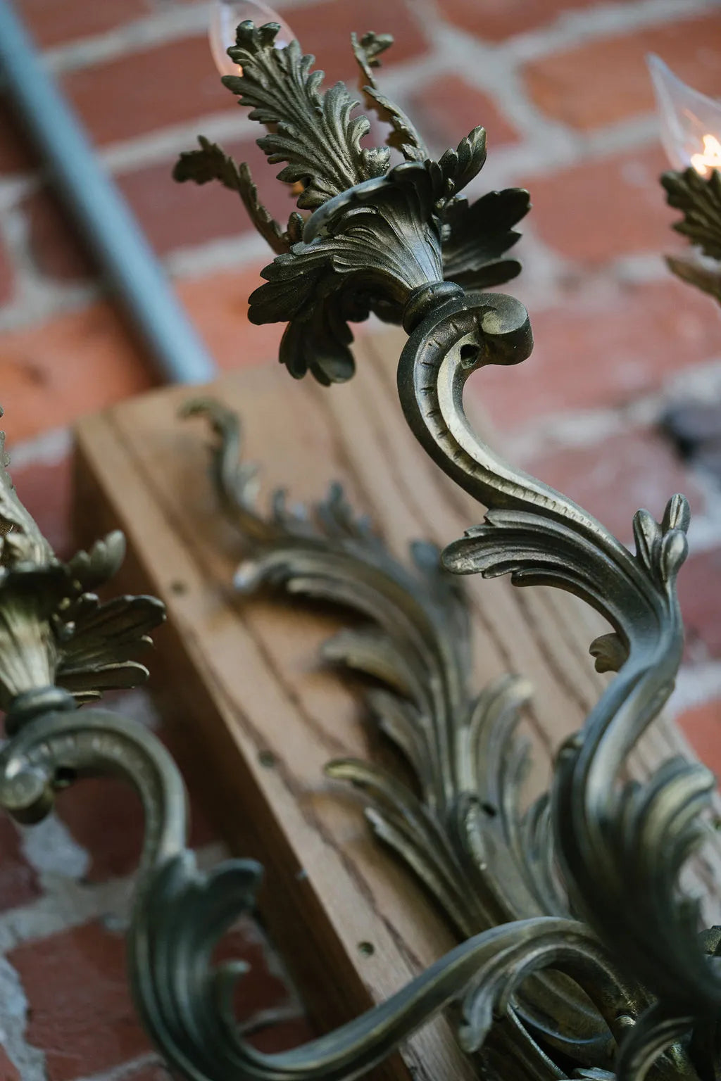 Decorative metal fixture with intricate designs against a brick wall.