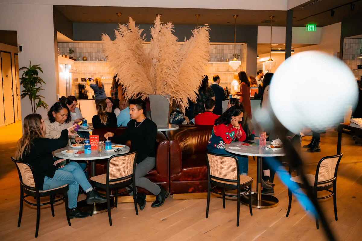People sitting at tables in a modern indoor setting with decorative plants and furniture.