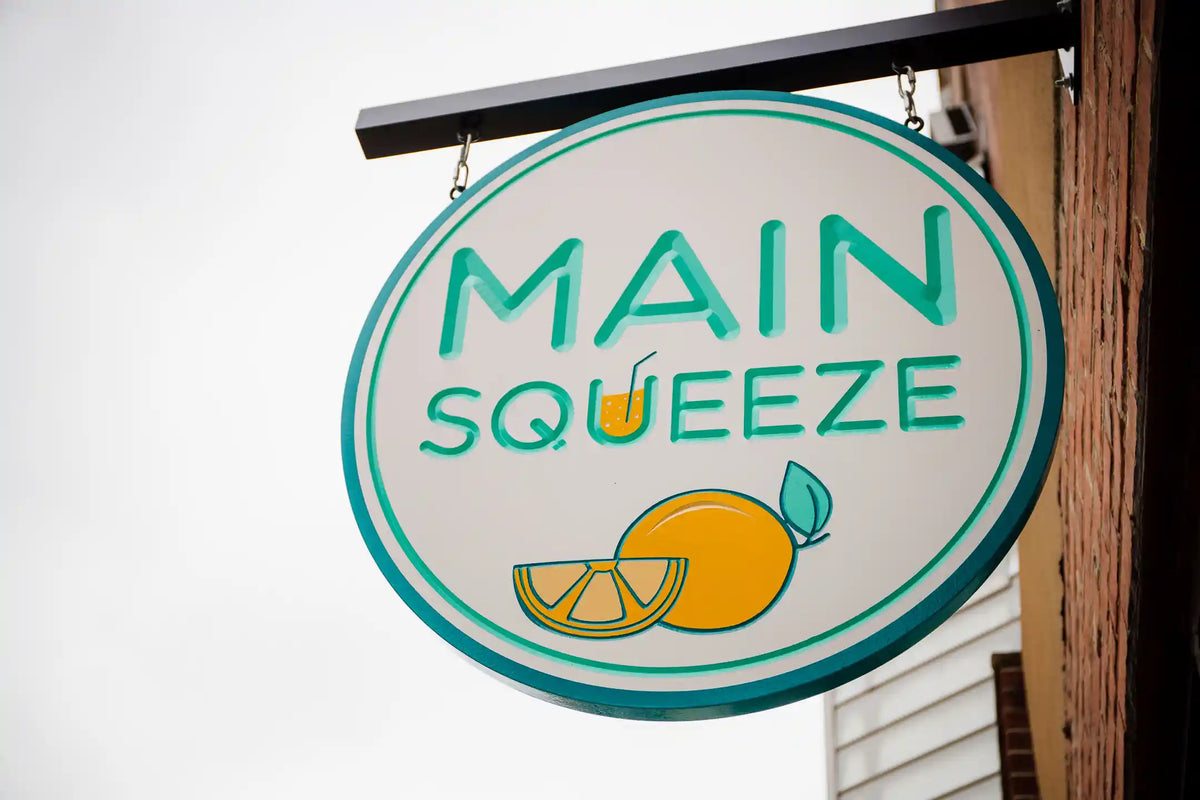 Round sign with 'MAIN SQUEEZE' and lemon graphics on a white background