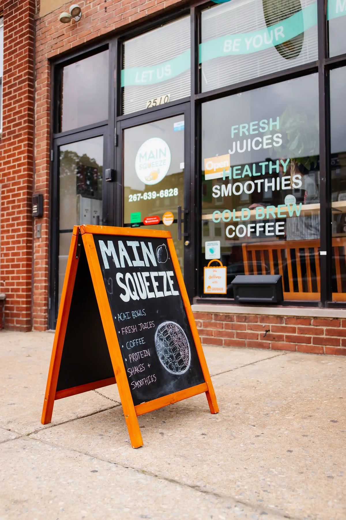 Outdoor sign for 'Main Squeeze' with store front in the background