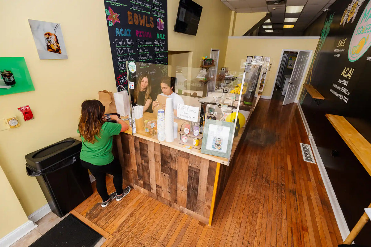 Person in a green shirt interacting with a counter inside Main Squeeze store with various items on display.