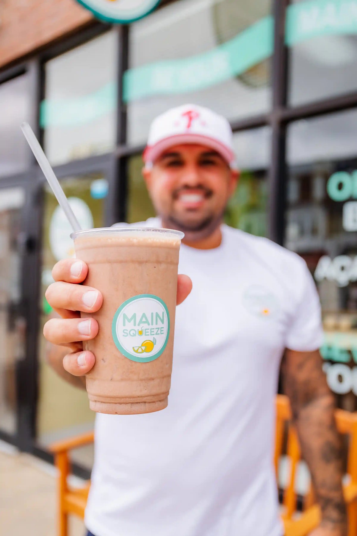 Man holding a Main Squeeze smoothie cup with a blurred background