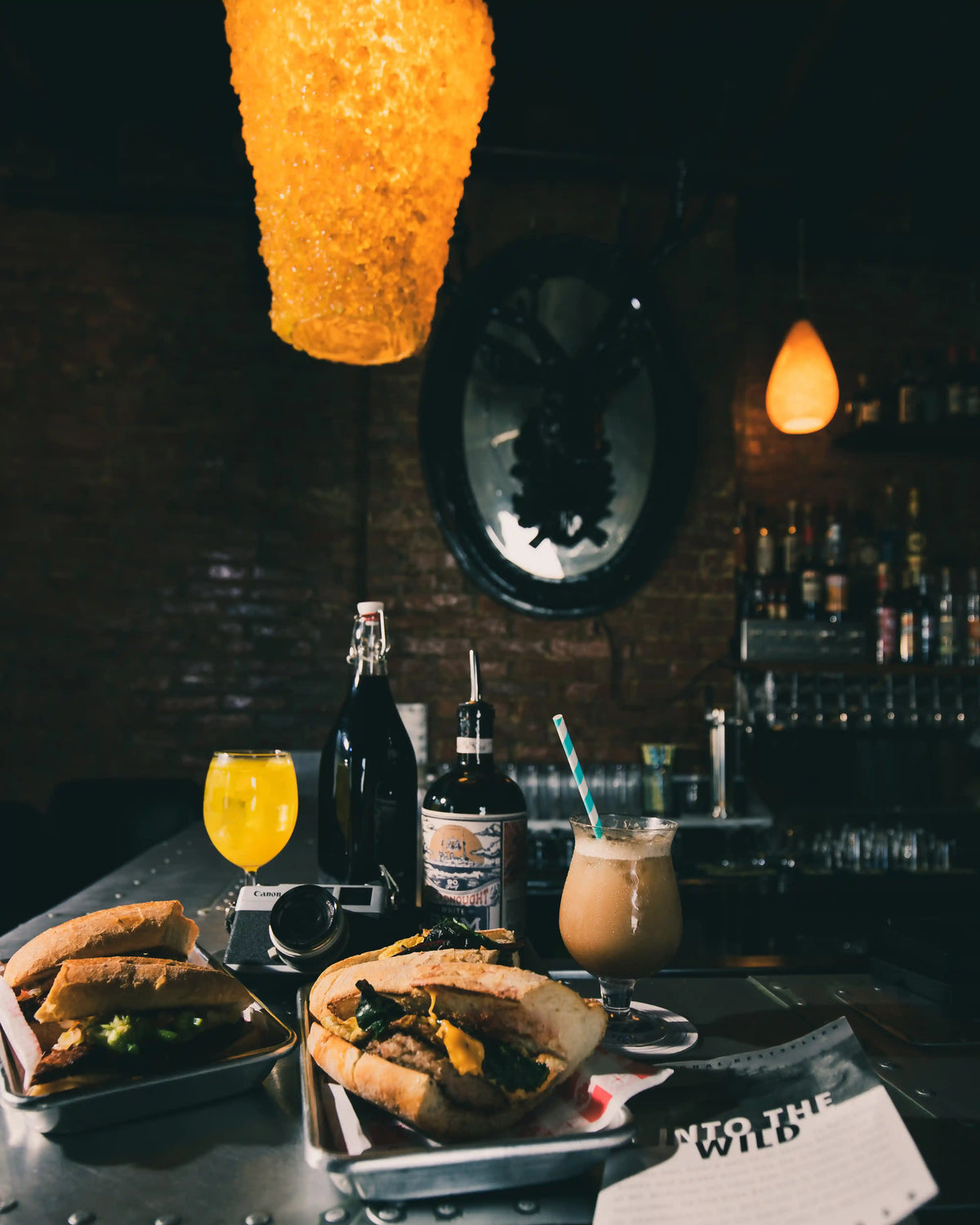 Dark bar setting with food and drinks on a bar, dimly lit.