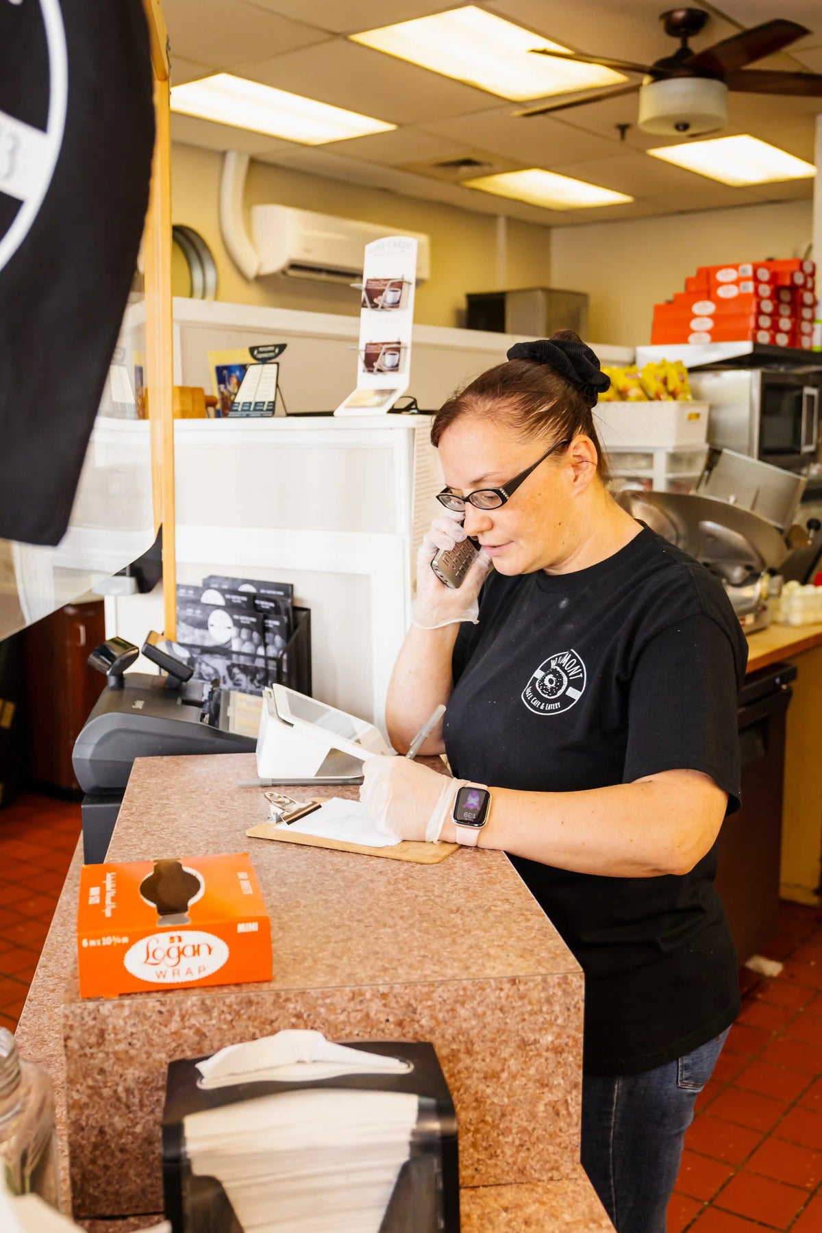 Person in a black shirt talking on a phone in a fast-food restaurant.