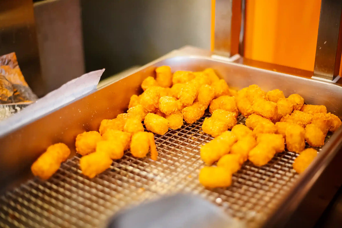 Frying tater tots in a deep fryer basket.